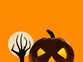 halloween pumpkin and zombie hand rising on orange background