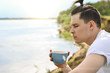 © ivan4es - Young man drinking coffee on the beach in Sunny summer day