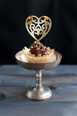 Wall Mural - Sweet cupcake with chocolate cream and topper in the shape of a gold heart