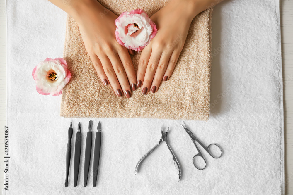 Female hands with brown manicure on towel and instruments, top view