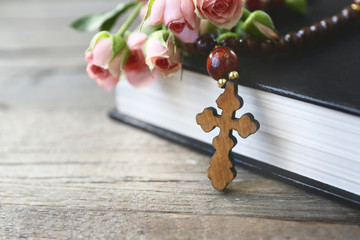 Wall Mural - Wooden cross with flowers and book, closeup