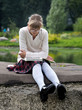 © kozorog - Portrait of a schoolgirl. Girl with glasses reading a book in a city park. Pond, green trees