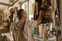Raftsman In Wood Workshop Looking Taking Out Tools From Shelf