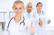 © rogerphoto - Happy doctor woman  with medical staff at the hospital. Thumbs up!