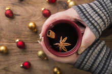 Cup Of Mulled Wine In Female Hands With Cinnamon Stick, Star Anise And Christmas Balls
