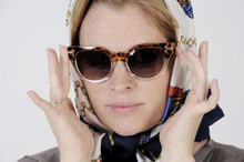 Young Woman Is Wearing Scarf And Sunglasses In A Grace Kelly Style. Studio Shot With Light Background. Isolated.
