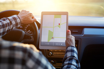 Man in car and holding tablet with map gps navigation