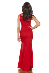 back view of young beautiful woman posing in a long red dress on a white background