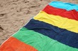 © Gary Perkin - Colorful beach towel on the sand on a bright sunny day, red yellow blue green orange