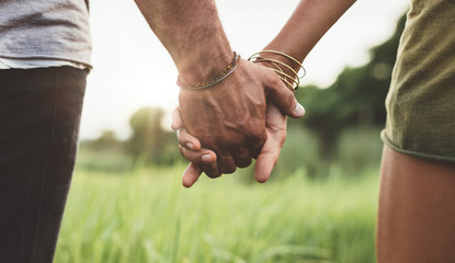 young couple holding hands in the field