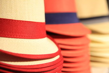 Straw Hats In Red And Black, Stacked Up For Sale In A Store In Shallow Focus.