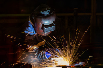 Welder is welding steel in factory