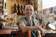 © Kzenon Premium - Violin maker in his workshop looking satisfied