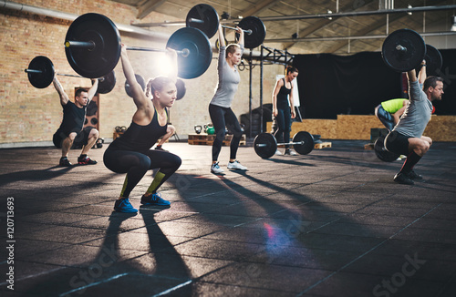 Fotomural Adults lifting large barbells in fitness class