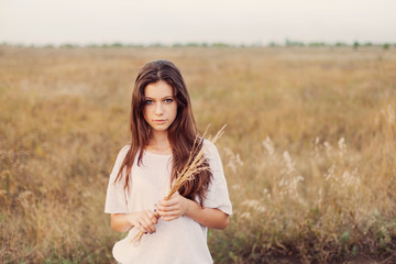 Young girl with long brown hair holds a bundle of ears 