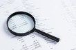 © interstid - Magnifying glass on financial statement paper. Analyzing business financial data.