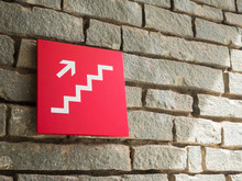 Red Stairs Going Up Sign On Wall Brick Background