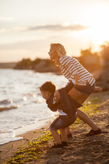 Wall Mural - Beautiful woman with a child four years playing on the beach near the sea