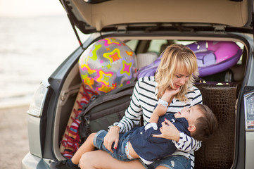 Wall Mural - Beautiful woman with a child of four years in the car are going to have a trip