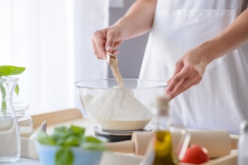 Woman adding powdered yeast to flour