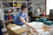 © Image Source - Female worker packing stacked paper in printing press workshop