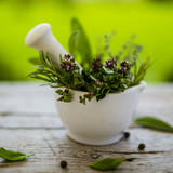Fototapeta Lawenda - Fresh and aromatic herbs in a mortar on old wooden table.