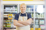 Fototapeta  - Confident Salesman Standing With Arms Crossed In Grocery Store
