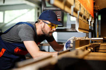 portrait of worker near metalworking machine, steel factory background.