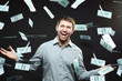 © pressmaster - Excited happy successful man standing under money rain against black background