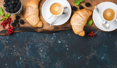 Wall Mural - Breakfast set. Freshly baked croissants with garden berries and coffee cups on rustic wooden board over dark grunge plywood backdrop, top view, copy space