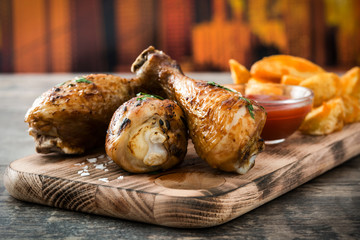 Poster - Roast chicken drumsticks and chips on wooden background

