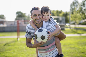 man with child playing football on field