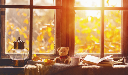 fall. cozy window with autumn leaves, book, mug of tea