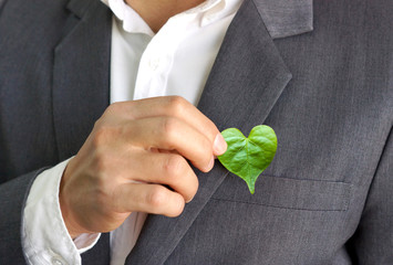 businessman holding a green heart leaf / business with corporate social responsibility and environme