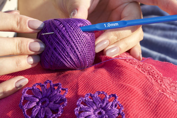 The woman knits earrings in the shape of a flower