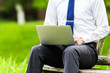 © beeboys - 屋外でパソコン作業をしているビジネスマン 自然の緑背景