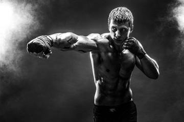 Wall Mural - Studio portrait of fighting muscular man in smoke.