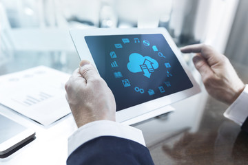 Close-up of modern businessman using tablet computer with application icons on screen at office table