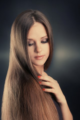 Wall Mural - Beautiful young girl with long hair on dark background. Beauty concept.