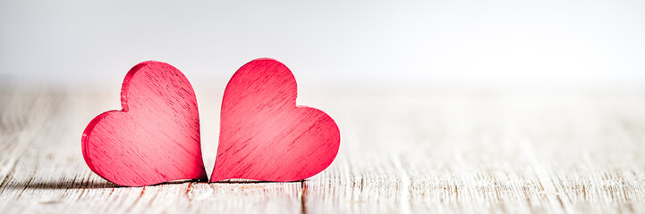 Two red hearts on wooden background