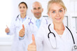 © rogerphoto - Happy doctor woman  with medical staff at the hospital. Thumbs up!