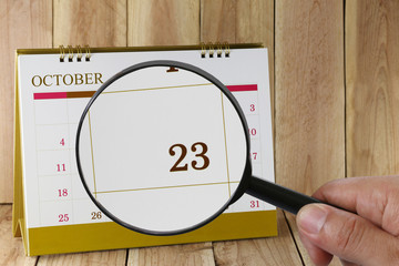 Magnifying glass in hand on calendar you can look Twenty-three d