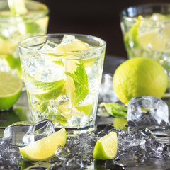 Mojito cocktail on a dark background with lime and ice