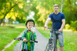 © Ermolaev Alexandr - young boy with a bottle of water is learning to ride a bike with father