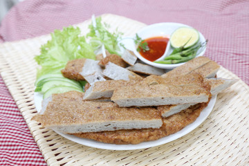 Vietnamese fish paste cake or cha ca on white plate with herbs,