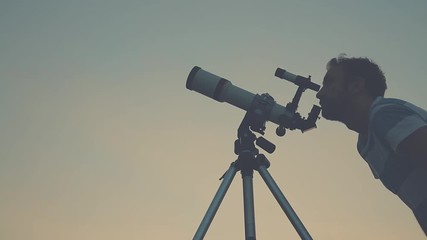 Wall Mural - man stargazing through a telescope.