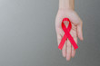 Female hands holding red ribbon HIV, AIDS awareness ribbon, healthcare and medicine concept. copy space.