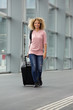 © mimagephotos - African american female walking with suitcase and backpack