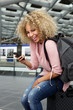 © mimagephotos - Happy female traveler sitting on suitcase with cell phone