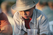 Portrait Of Boy Wearing A Shell Necklace And A Sunhat On Holiday.